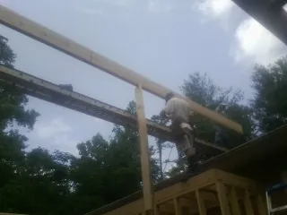 Carpenter setting a ridge beam over a new addition frame — Ice Dam Removal by Roofing Brothers in Grifton