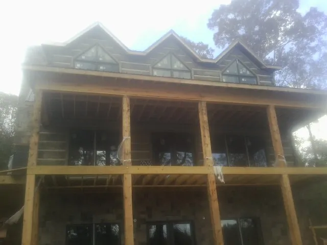 Dormers and porch framing on a large log home under construction — Roof Coating work by our crew in Grifton