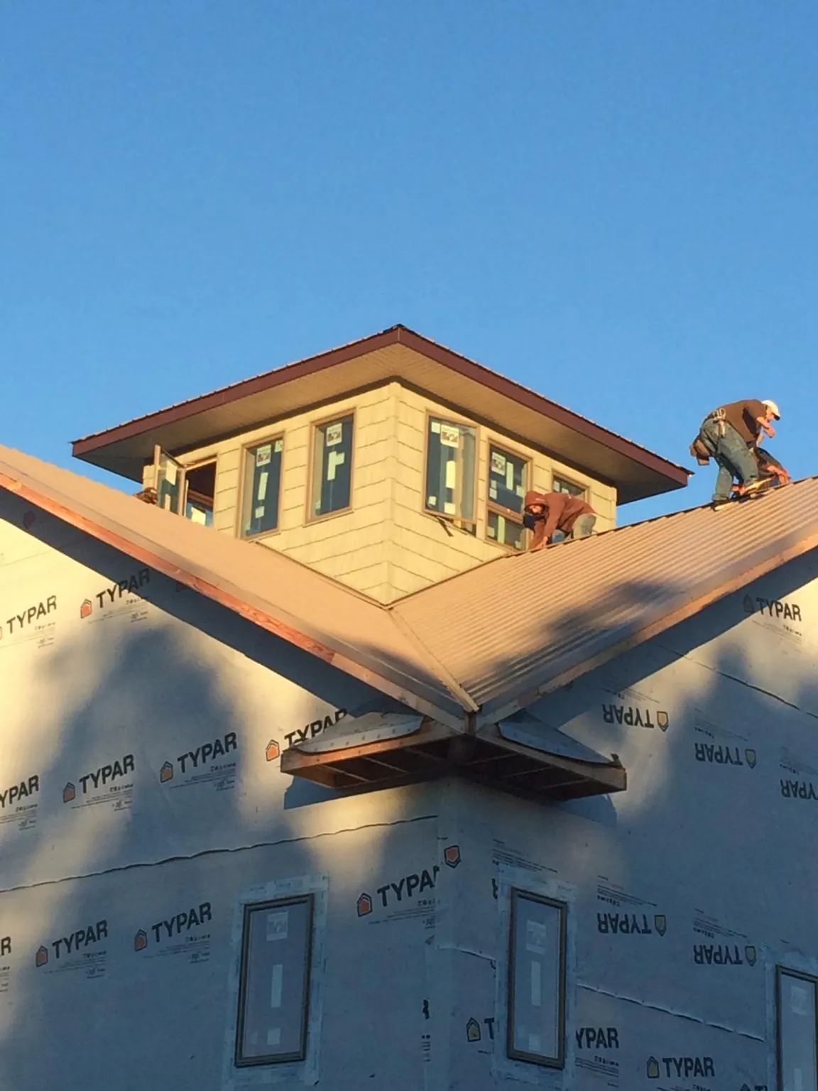 Roofers working around a rooftop cupola on a new metal roof at sunset — Roof Waterproofing in Grifton by Roofing Brothers